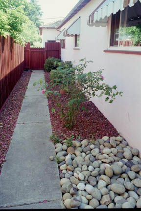 Before any changes - Sidewalk and red gravel, red fence, metal awning on window